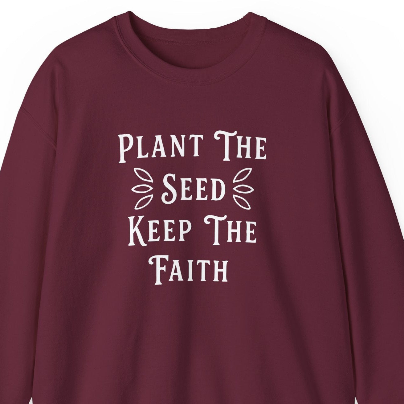 Maroon sweatshirt with white text 'Plant The Seed Keep The Faith' on a white background