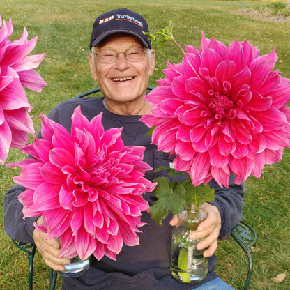Man sitting outdoors holding large pink flowers