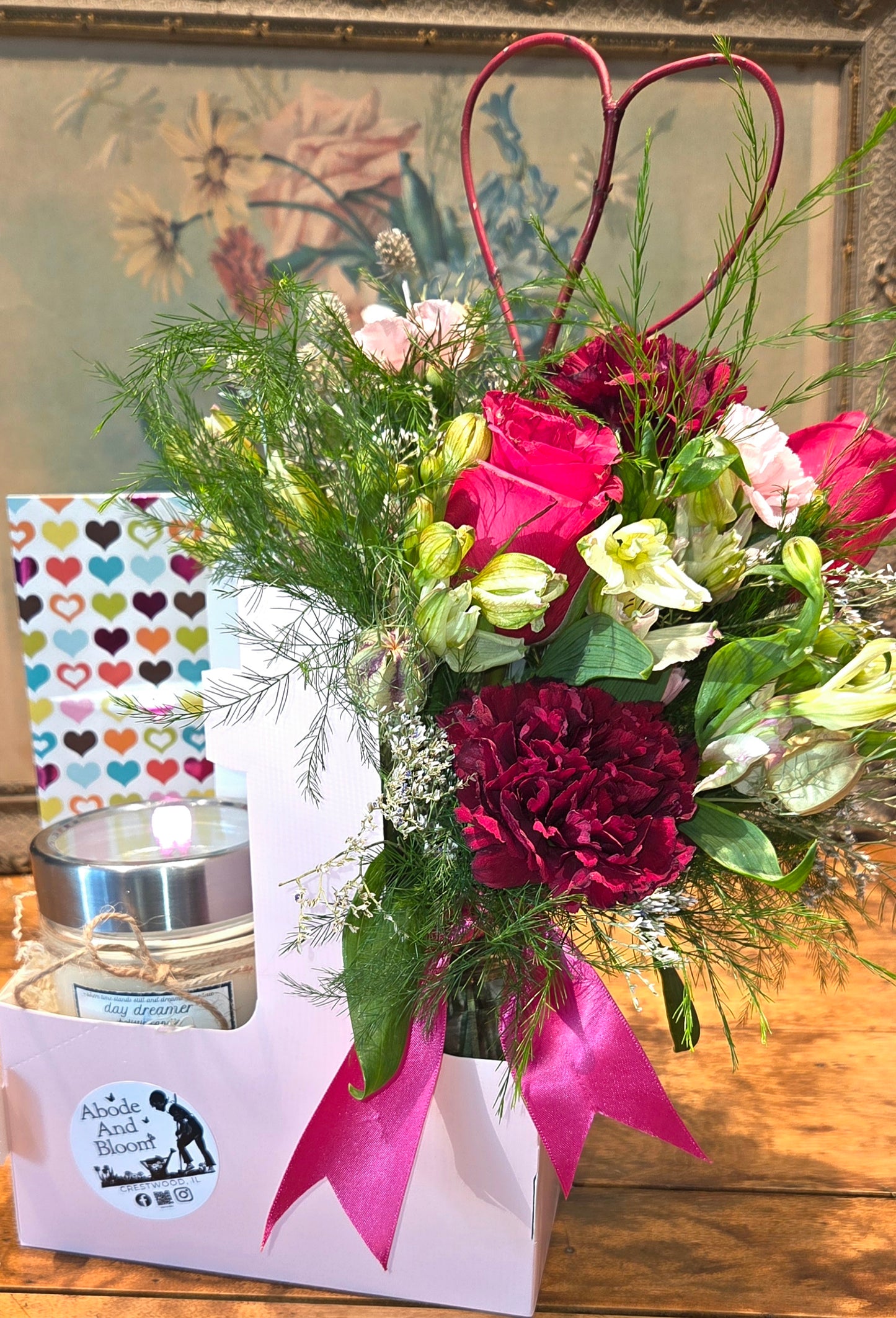 Bouquet of flowers with a candle and decorative box on a wooden surface