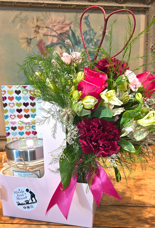 Bouquet of flowers with a candle and decorative box on a wooden surface